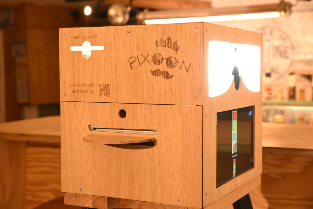 Façade du photobooth Pixoon Façade du photobooth Pixoon en bois : écran tactile, logo, QR code et fente d’impression