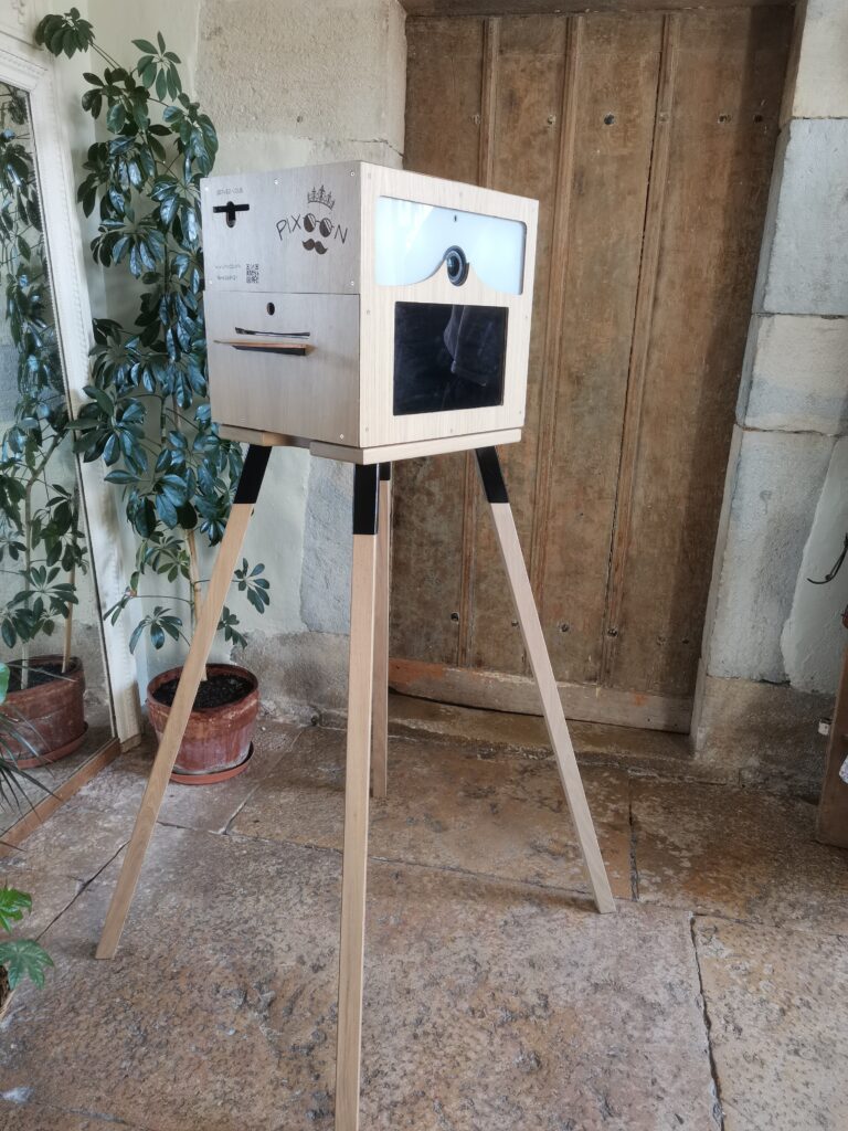 Location photobooth à Lyon, Pixoon Photobooth Pixoon de fabrication artisanale sur son chevalet devant une porte en bois