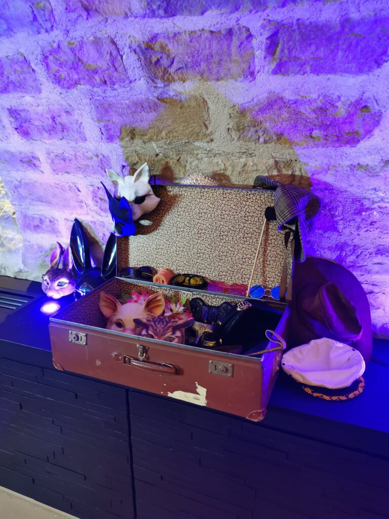 Valise d’accessoires pour photobooth (masques, chapeaux) sous lumière violette