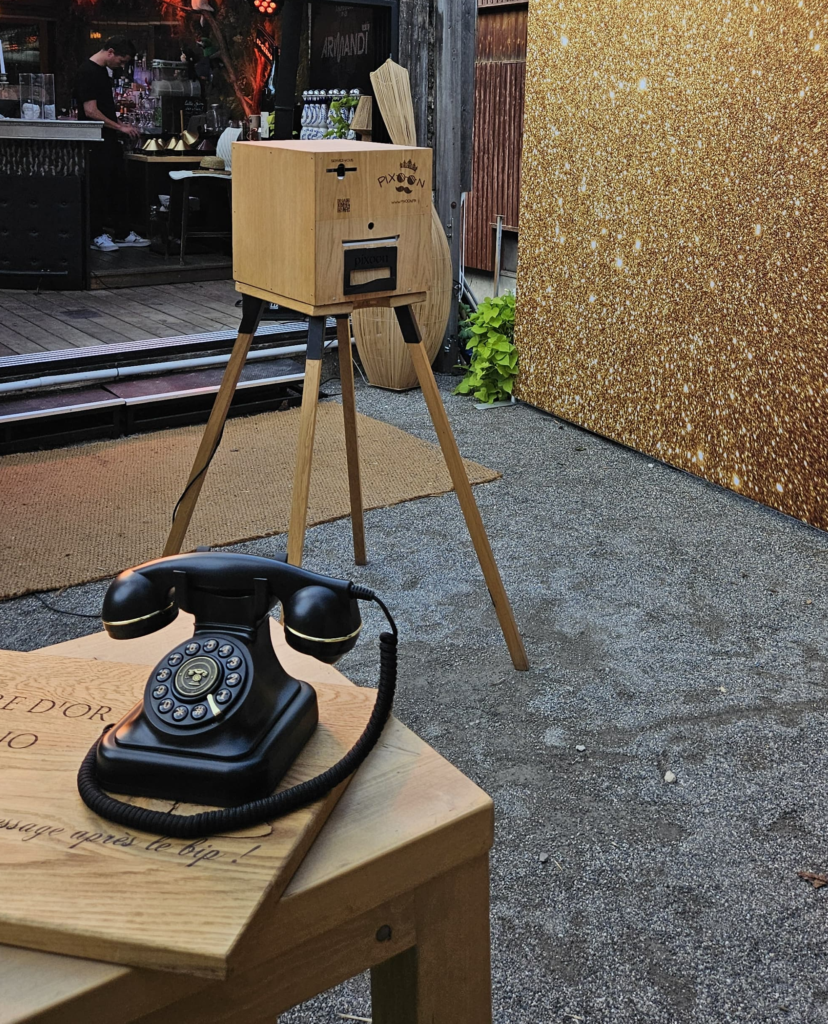 Livre d’or audio : téléphone vintage sur sa table, photobooth Pixoon et fond à paillettes derrière