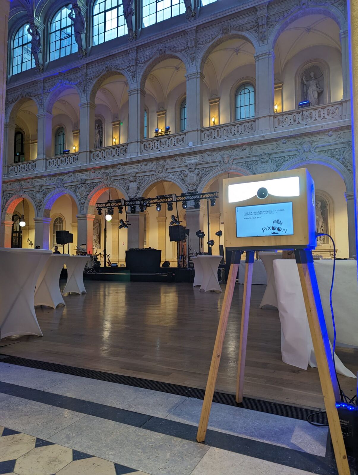 Photobooth Pixoon sur son chevalet dans un grand hall à arcades éclairé en bleu, lors d’une soirée