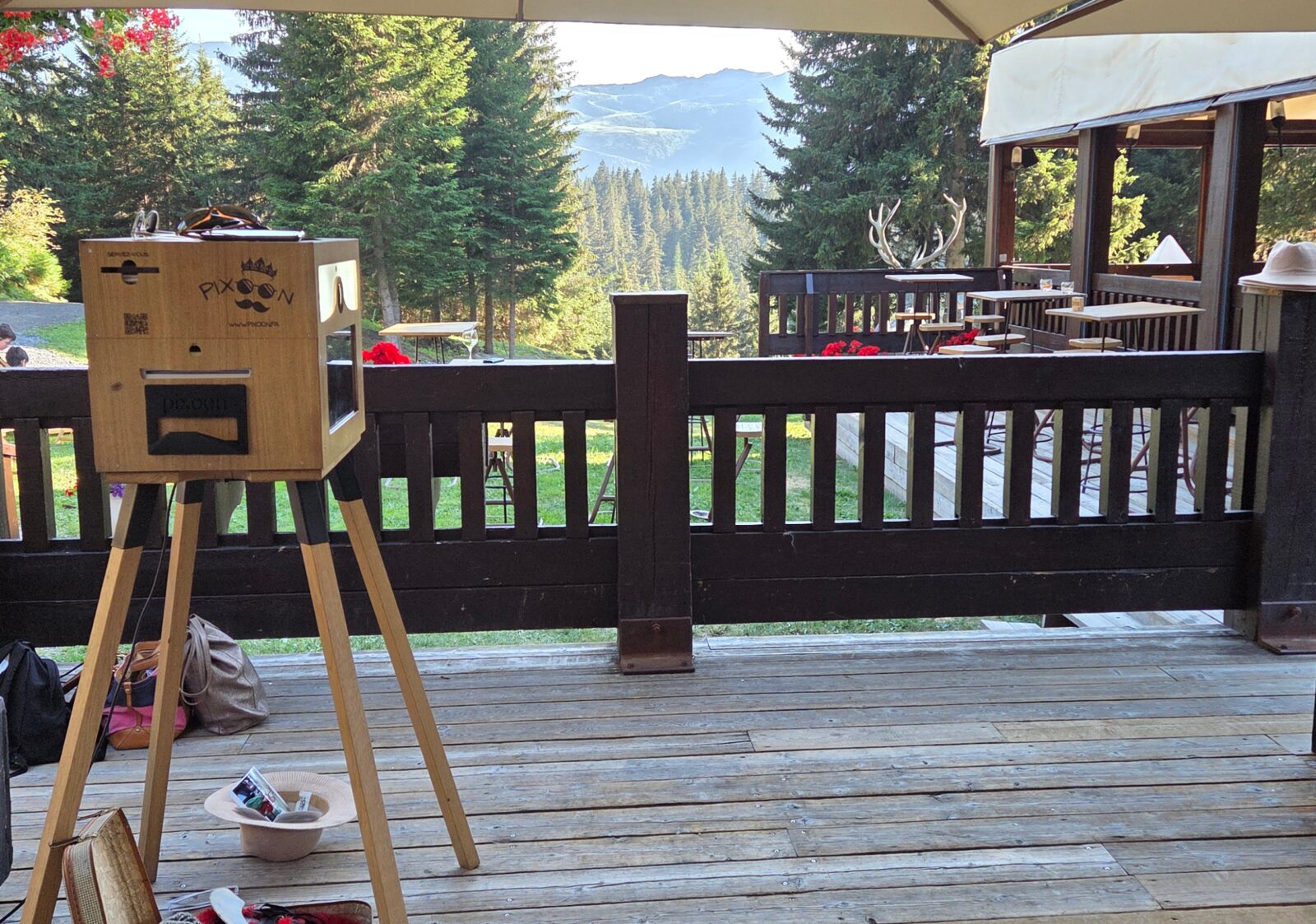 Photobooth Pixoon en bois sur son chevalet, installé sur une terrasse en bois face aux montagnes
