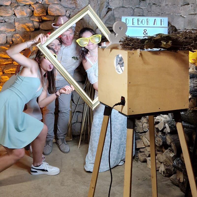 Trois invités posent avec un cadre photo devant un mur en bois