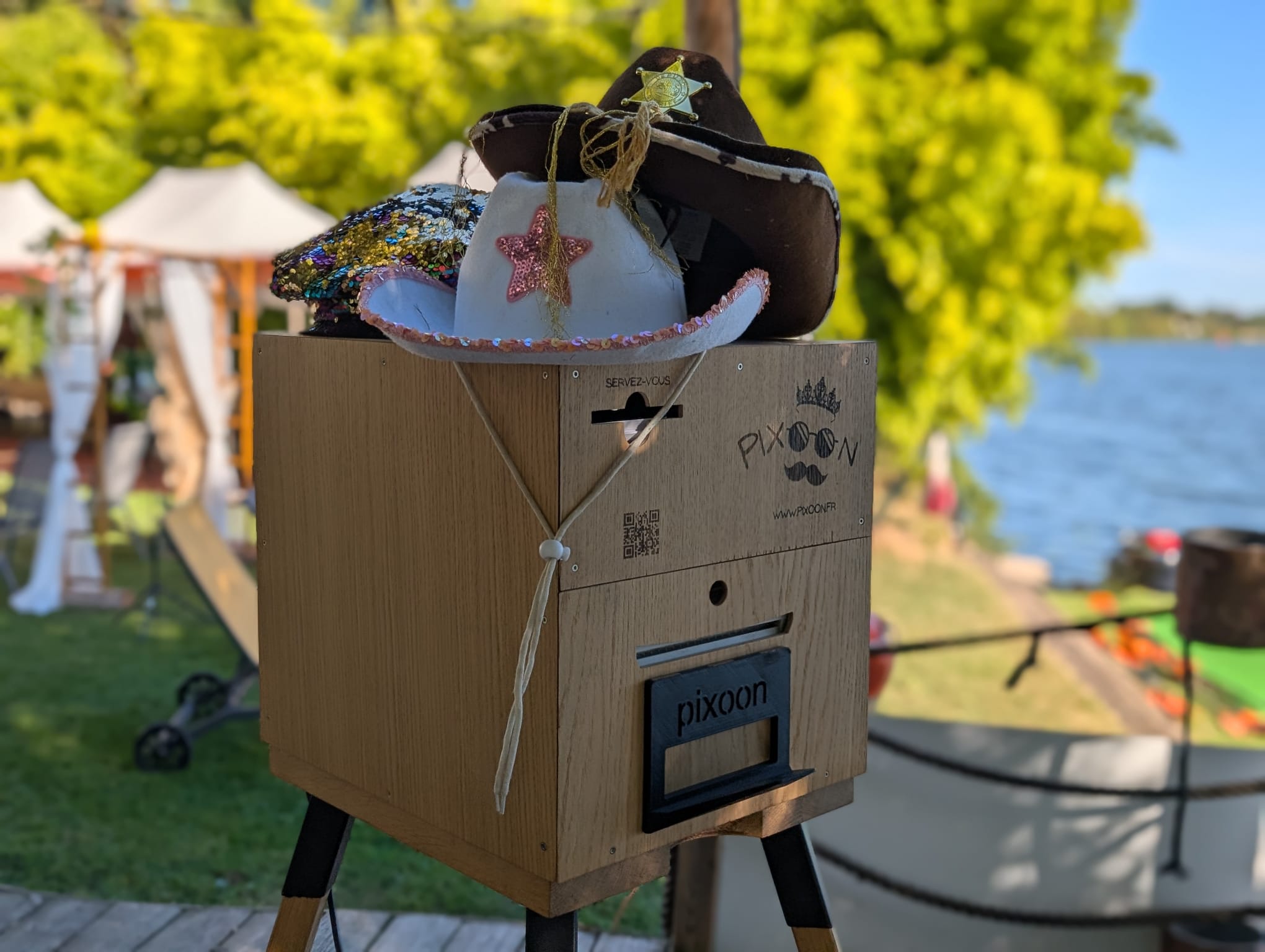 Photobooth Pixoon pose sur son chevalet au bord de la Saone, avec des chapeaux sur la box
